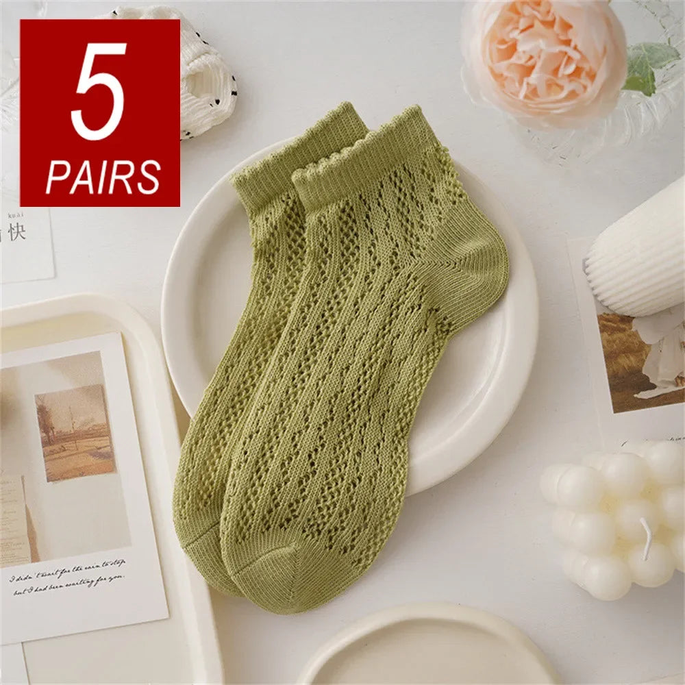 Five pairs of light green breathable mesh lace tube socks displayed on a white plate.