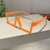Orange square semi-rim metal eyeglasses resting on a white surface.