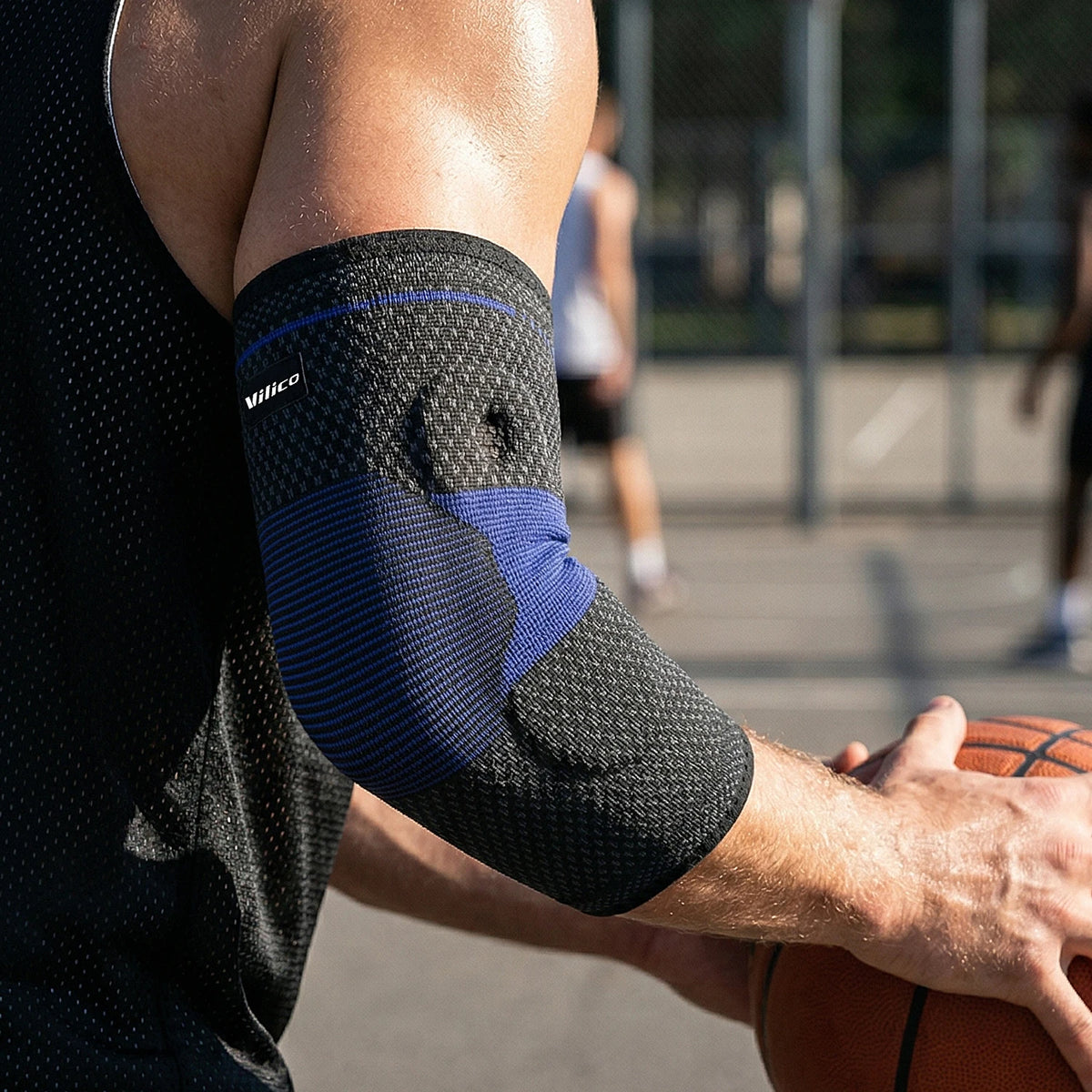 A person wearing a black compression sleeve on their forearm and elbow while playing basketball.