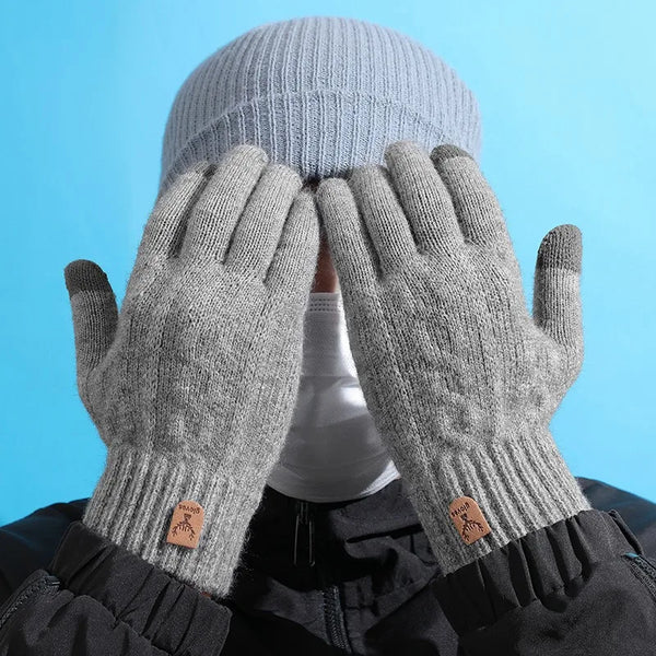 A pair of light gray knitted winter gloves covering a person's head.