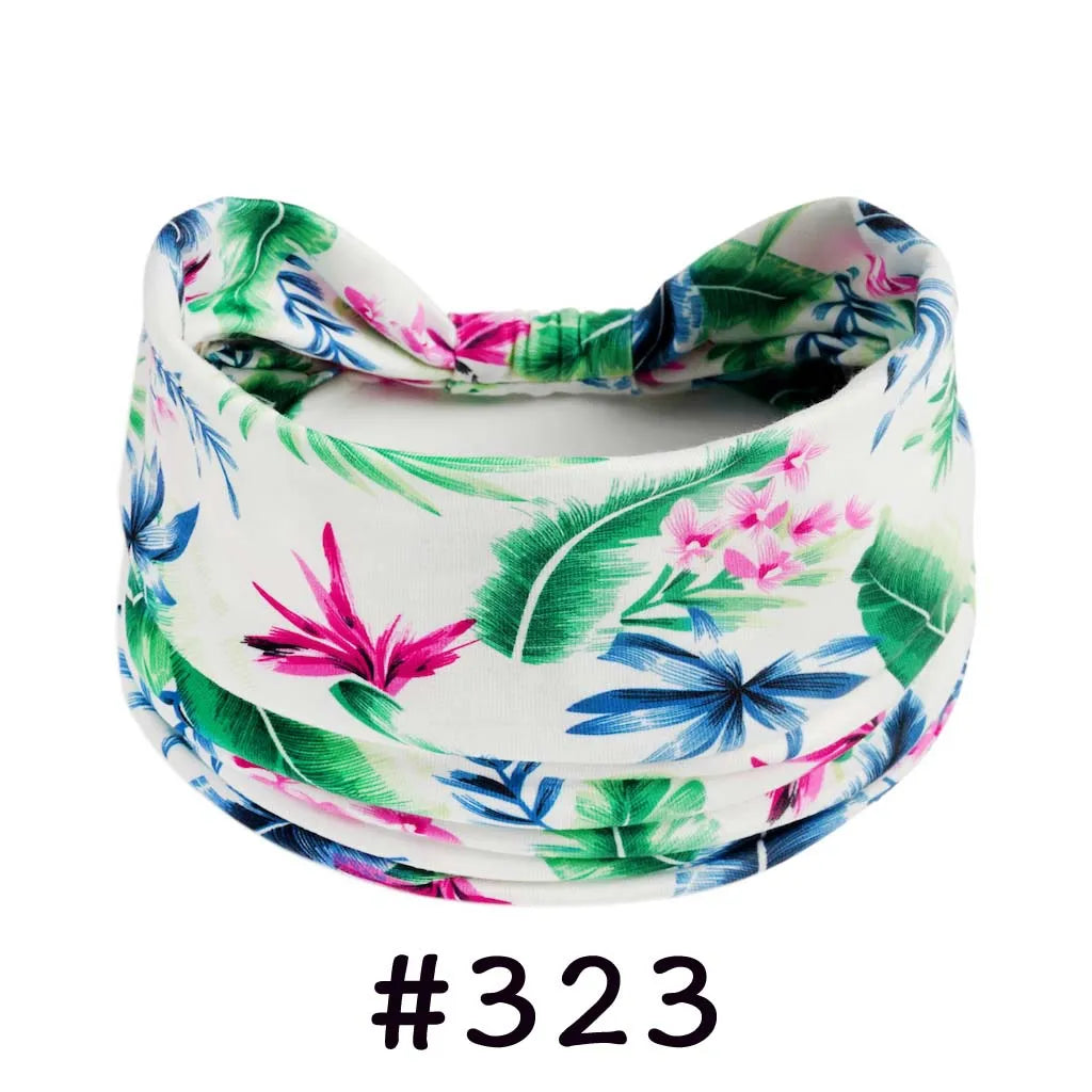 A floral patterned cotton headband tied in a knot, featuring green and pink leaves and blue flowers.