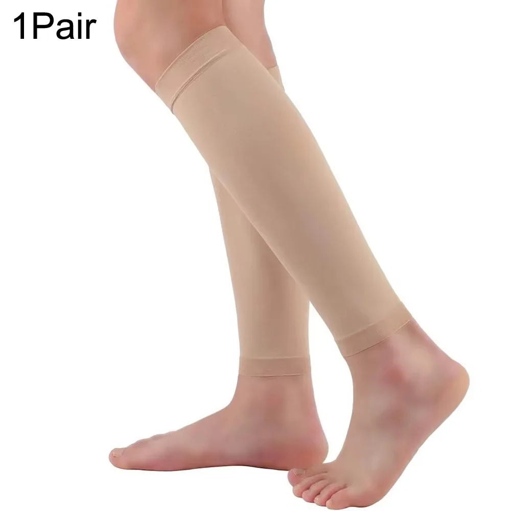 One pair of beige calf compression sleeves worn on a person's leg.