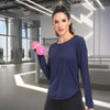 A woman wearing a navy blue loose fit sun protection t-shirt and black leggings in a modern gym setting.