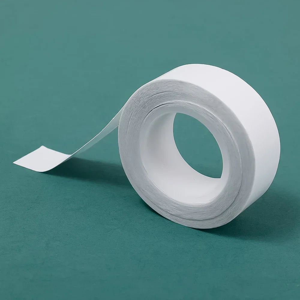 Roll of white invisible double-sided fashion tape lying on a teal surface.