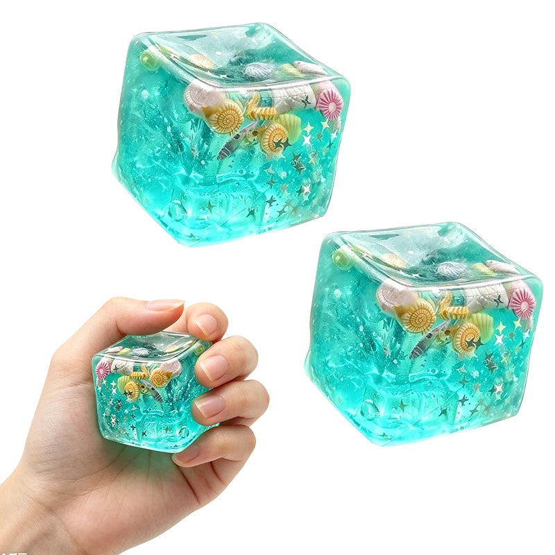 A hand holds a translucent teal squishy stress relief fidget cube filled with colorful, squishy objects.