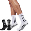 A pair of white athletic grip socks with black patterned soles worn on a person's leg.