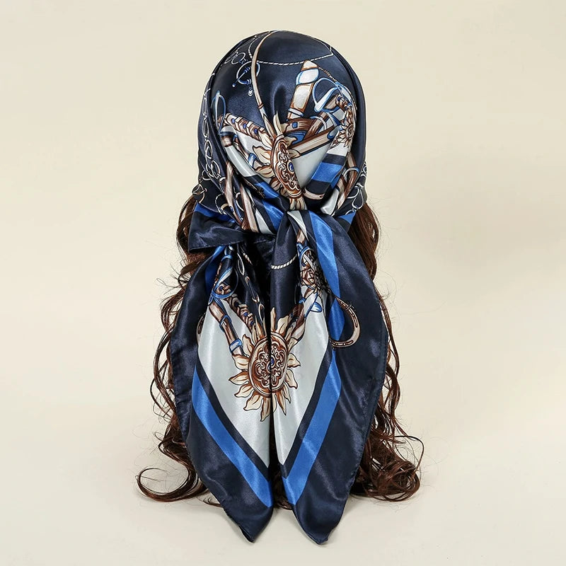 A dark blue satin square scarf featuring intricate silver and gold embroidery for hijab or hair