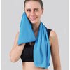 A woman wearing a black sports top holds up a bright blue instant cooling towel.