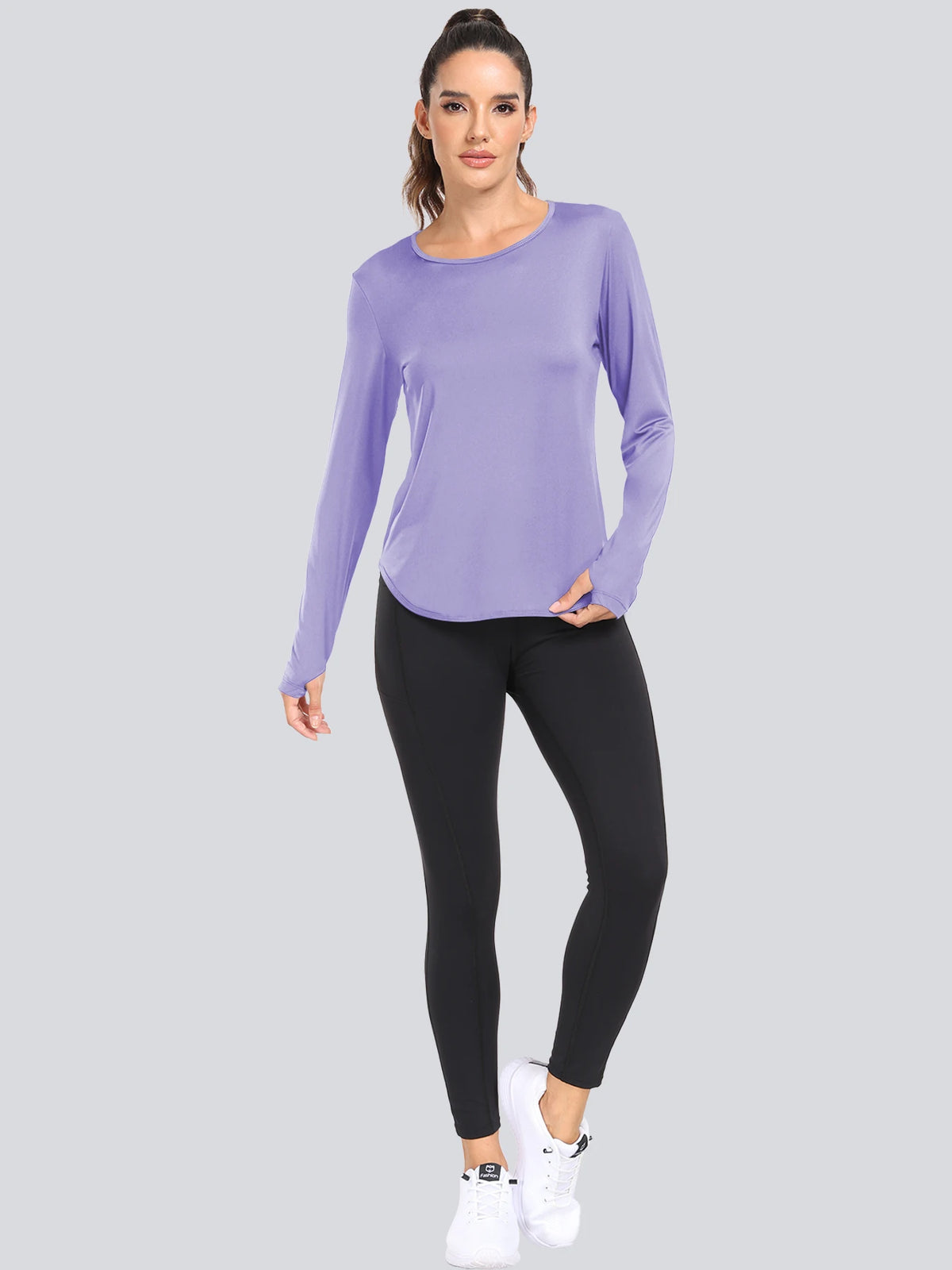 A woman models a purple long-sleeved loose fit sun protection t-shirt and black leggings.