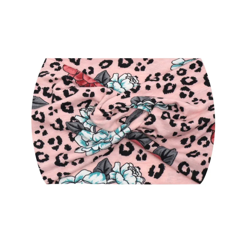 Pink leopard print fabric with white floral embroidery, used as a wide knotted headband.