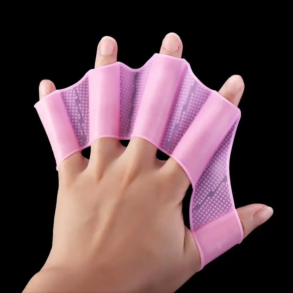 A hand is holding a pink silicone swim training flipper, showing the product's texture and shape.
