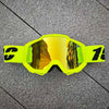Une paire de lunettes de moto et d'ATV jaune vif posées sur une surface gris foncé.