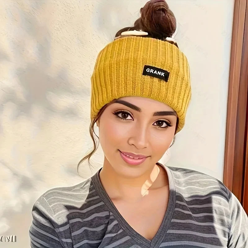 A woman wearing a yellow knitted headband with the word GRANK on it, against a light background.