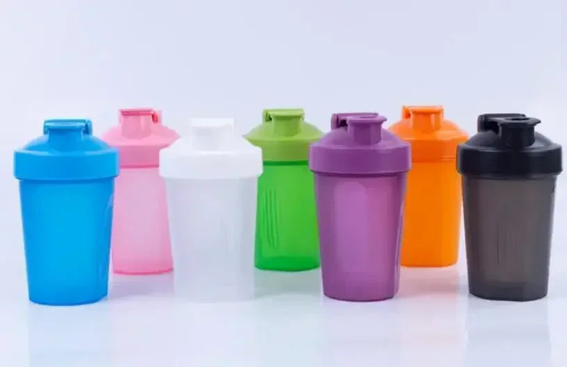 A row of colorful portable protein shaker bottles in various shades including blue, pink, white, green, purple, and orange.