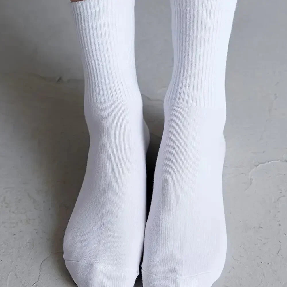 Une paire de chaussettes en tricot blanches mi-mollet respirantes, montrées sur un fond clair.