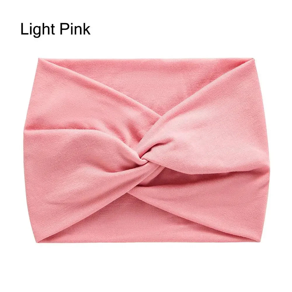 ربطة رأس من قماش وردي فاتح مطوية بعقد متقاطع لاستخدام اليوغا أو التمرين.