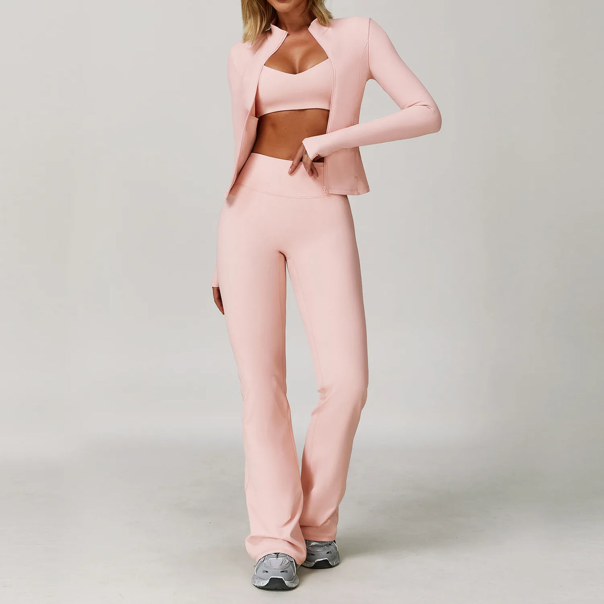 A woman models a pink 3-piece yoga sports set consisting of a cropped top, blazer, and matching pants.
