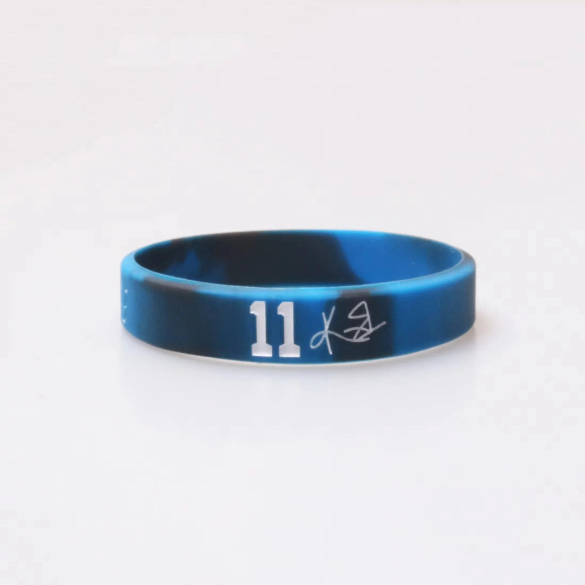 A dark blue silicone wristband with the number 11 and a signature etched on the surface.