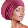 A model wearing a dusty rose silicone swim cap for long hair against a white background.