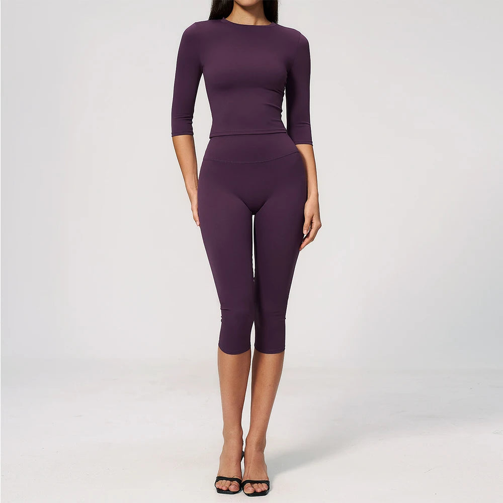 A woman wearing a long-sleeved purple yoga and fitness leggings set.