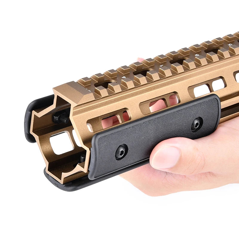 A hand holds a tactical rail panel kit for an airsoft gun, featuring a bronze-colored rail and black grip.