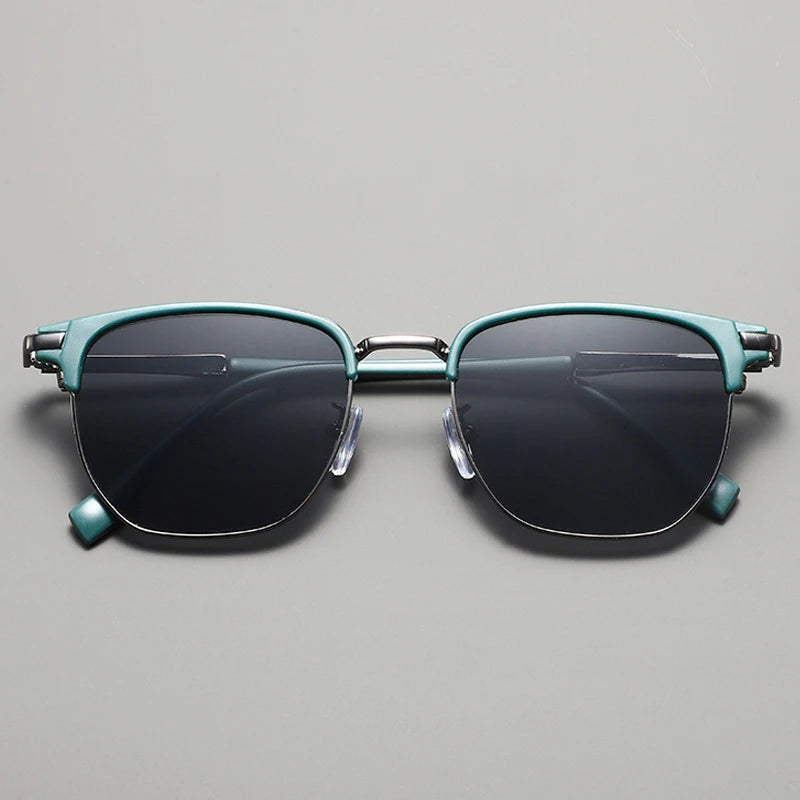 Teal-green metal frame sunglasses with dark lenses displayed against a light gray background.