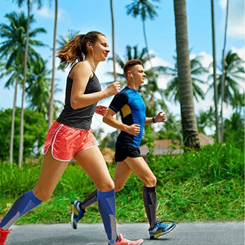 A woman and a man jogging outdoors in a tropical setting wearing compression socks.