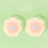 Une paire de cache-sein en silicone réutilisable de couleur rose pâle est présentée sur un fond vert clair.