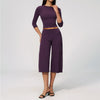 A woman models a purple yoga and fitness leggings set consisting of a long-sleeved top and high-waisted pants.