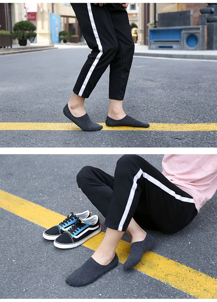 A person wearing black pants and gray socks is walking on asphalt with yellow lines visible.