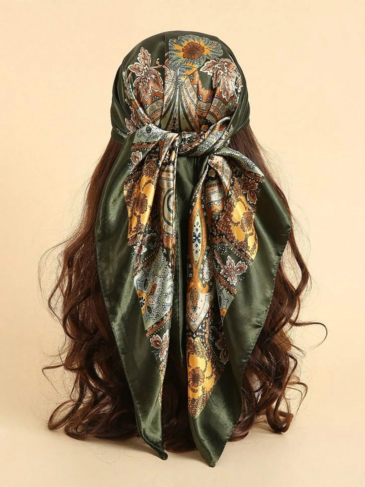 Pañuelo de satén verde oliva oscuro con estampado floral paisley bohemio, atado alrededor de cabello largo y castaño oscuro.