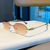 Rimless oval gradient sunglasses with gold-toned arms resting on a white surface.