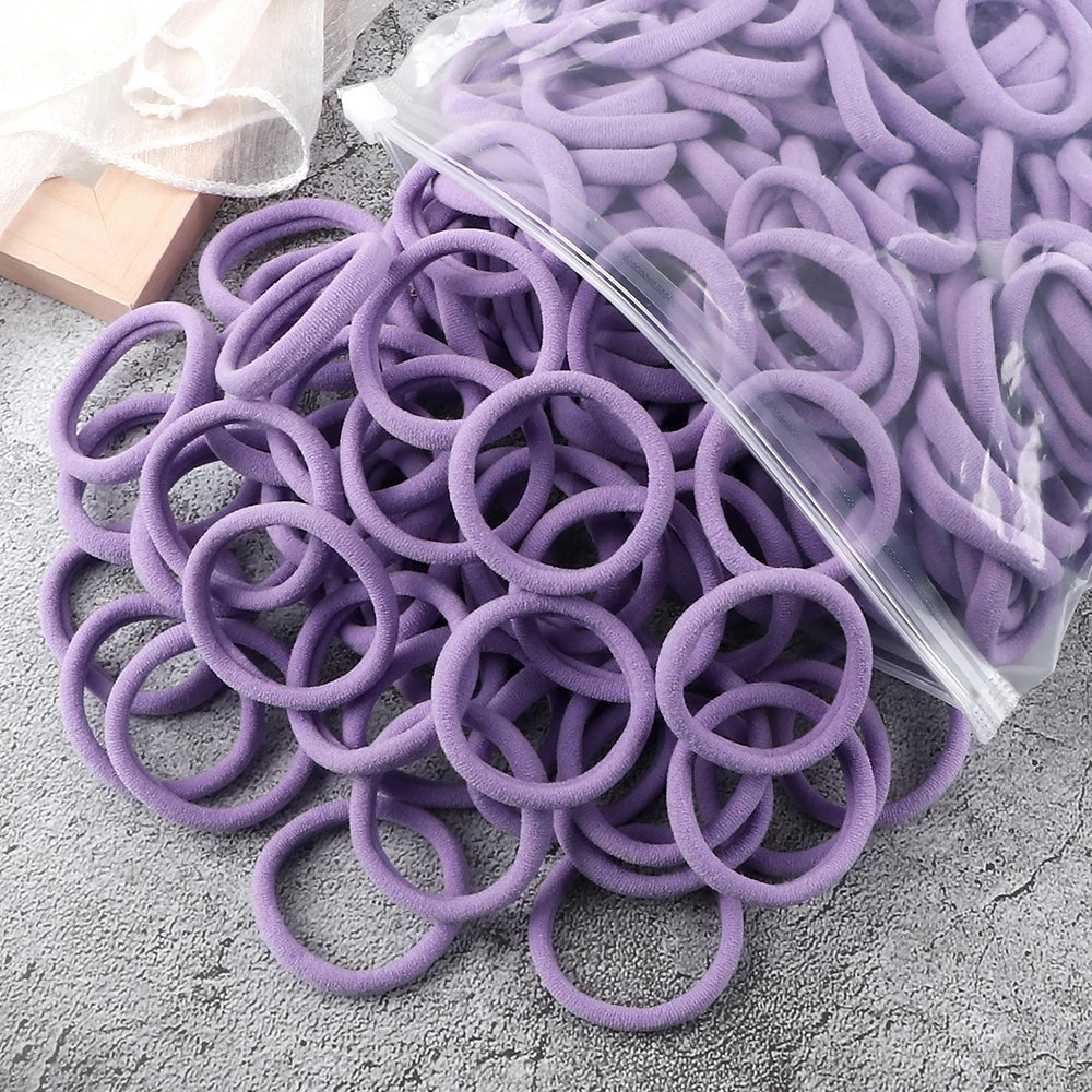 A pile of 50 pieces of mixed color elastic hair bands in purple and lavender shades.