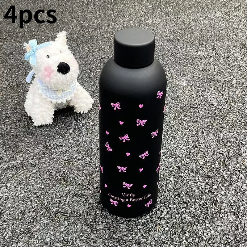 Cuatro pequeños imanes de silicona con forma de perro exhibidos junto a una taza de viaje aislada negra con diseños de maripo