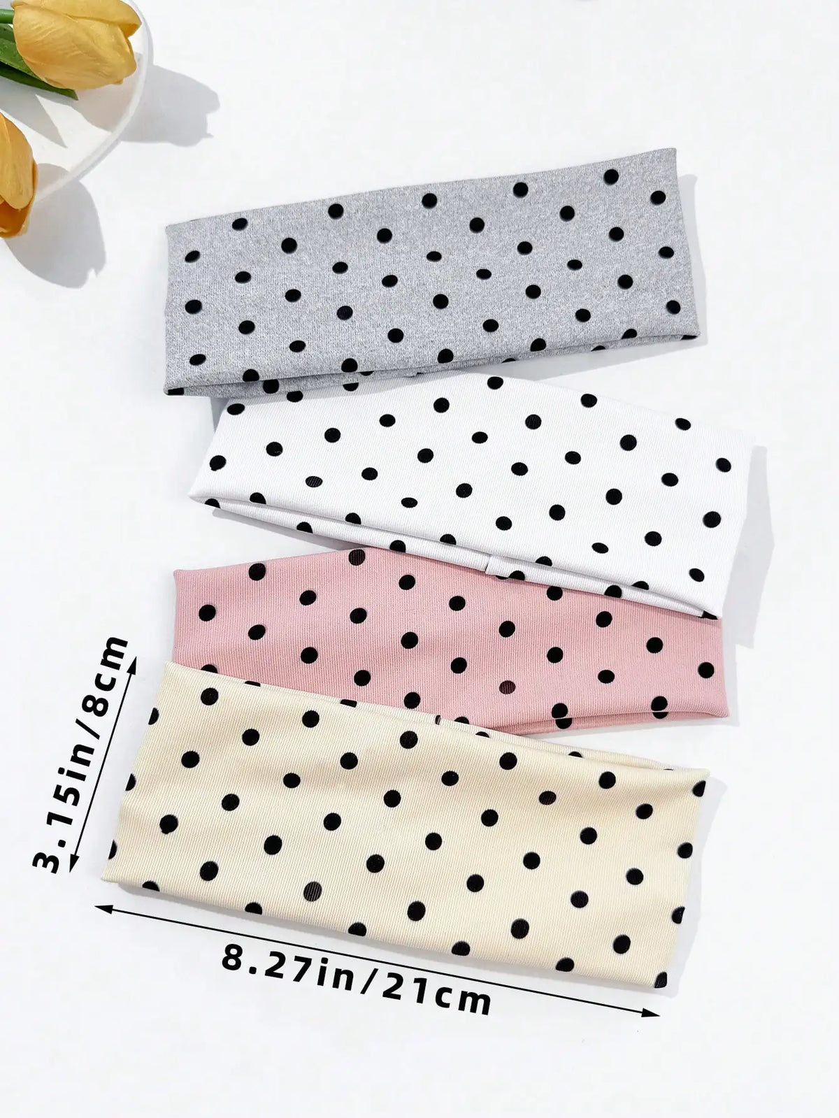 A set of four polka dot elastic hair bands in gray, white, and pink tones displayed on a white background.