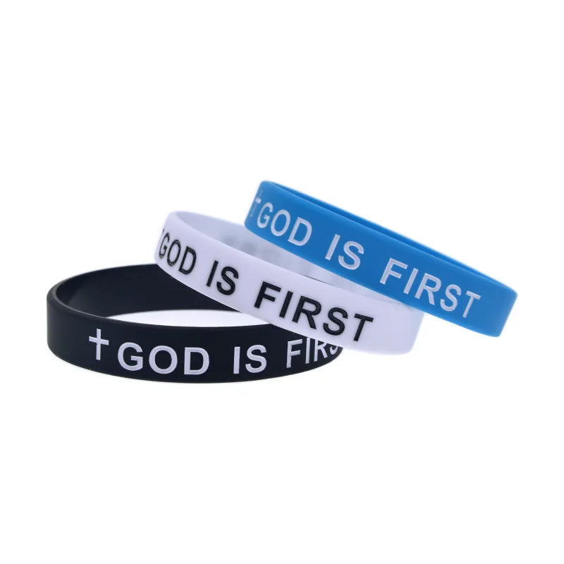 Drei Silikonarmbänder mit der Aufschrift GOD IS FIRST in Blau, Weiß und Schwarz.