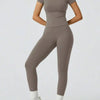 Eine Frau modelliert ein zweteiliges Yoga-Set aus Oberteil und Leggings in taupegrauer Farbe.