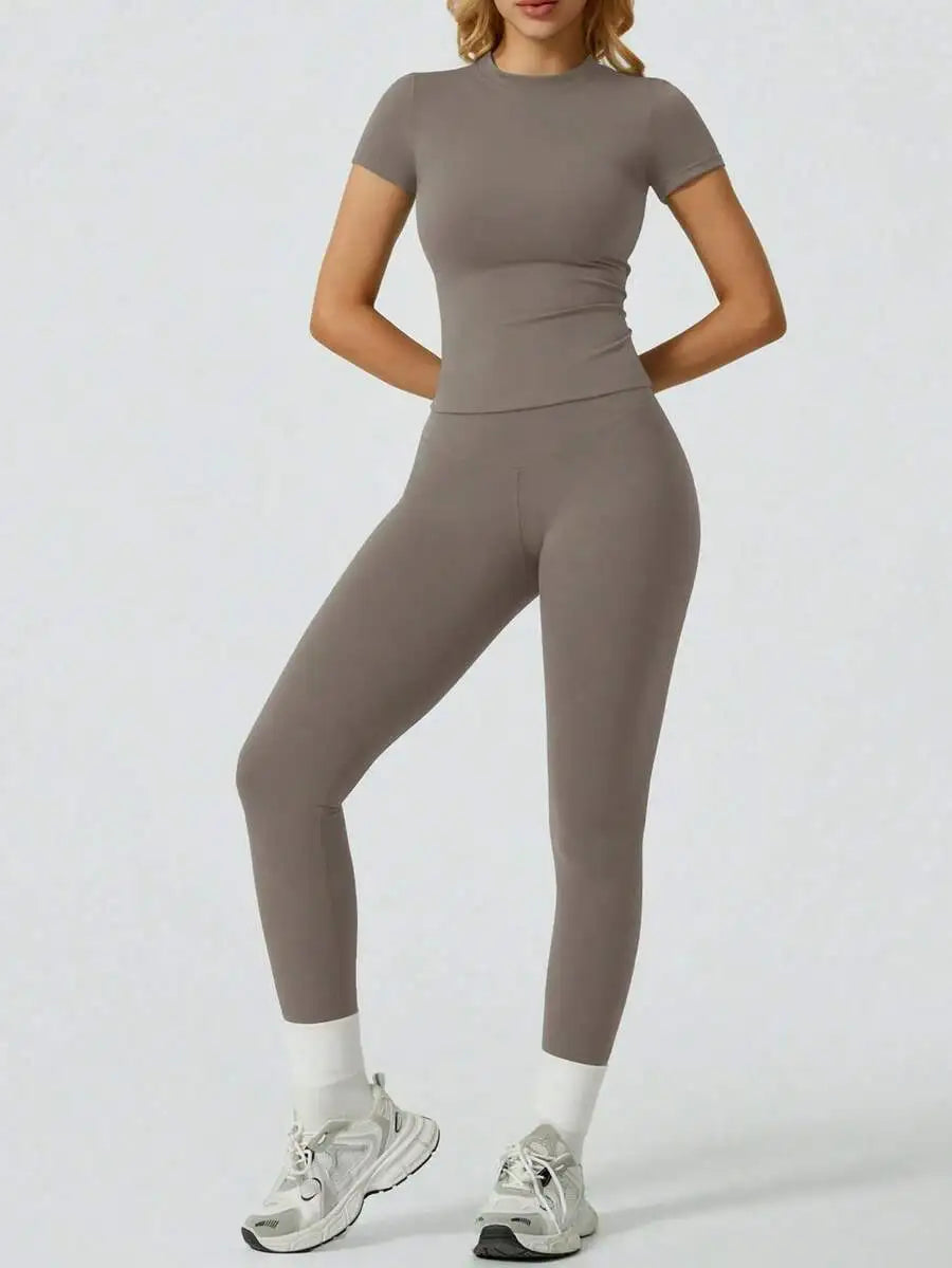 Eine Frau modelliert ein zweteiliges Yoga-Set aus Oberteil und Leggings in taupegrauer Farbe.