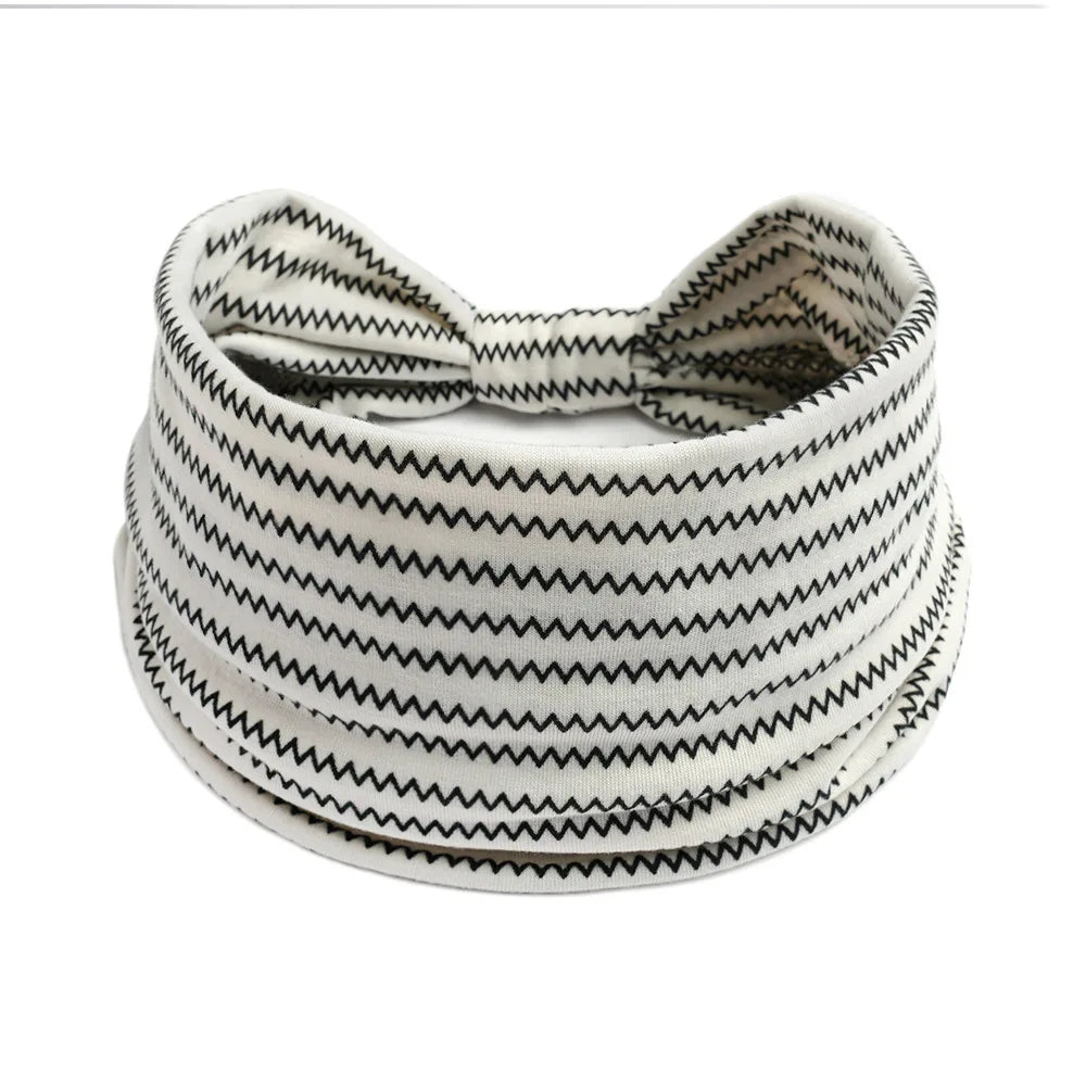 A white and black patterned cotton stretch headband coiled around itself.