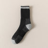 A close-up of black and gray merino wool thermal hiking socks with a ribbed cuff.