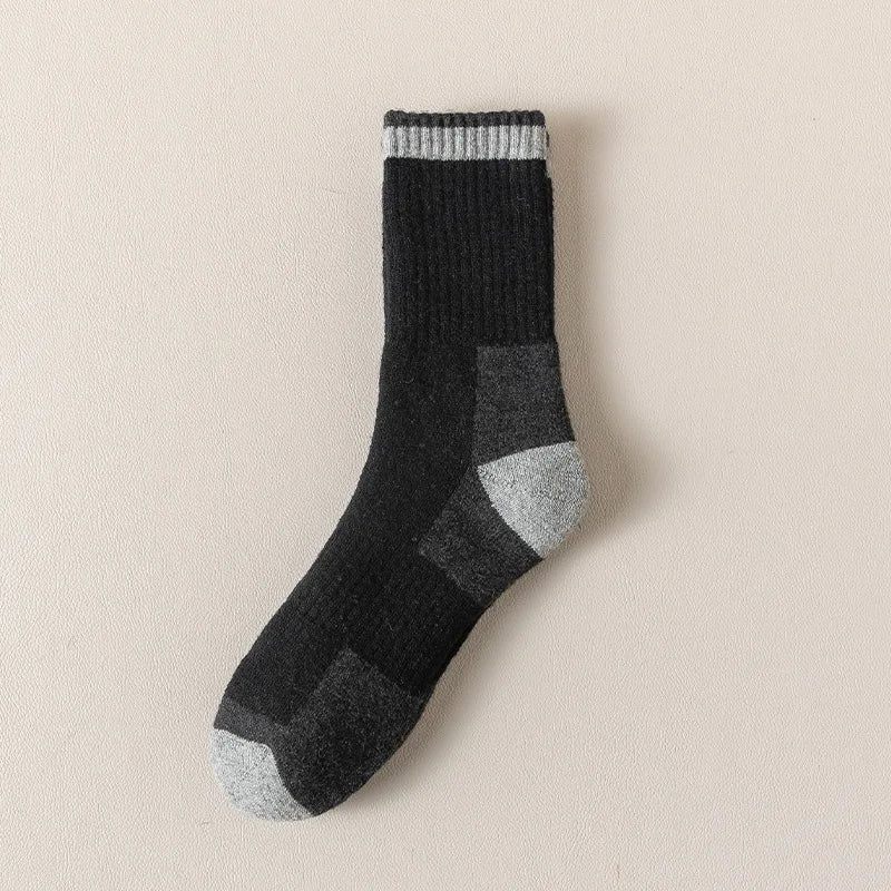 A close-up of black and gray merino wool thermal hiking socks with a ribbed cuff.