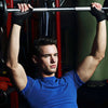 A muscular man lifts a barbell with fitness workout gloves in a gym setting.