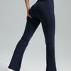 A model wearing dark navy high-waisted bootcut yoga pants and a matching crop top, standing in a side profile.