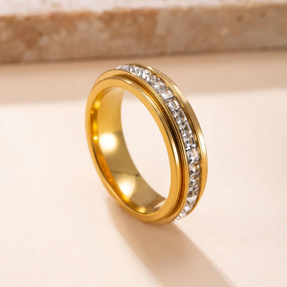 A gold-toned statement ring featuring a band set with clear cubic zirconia stones.