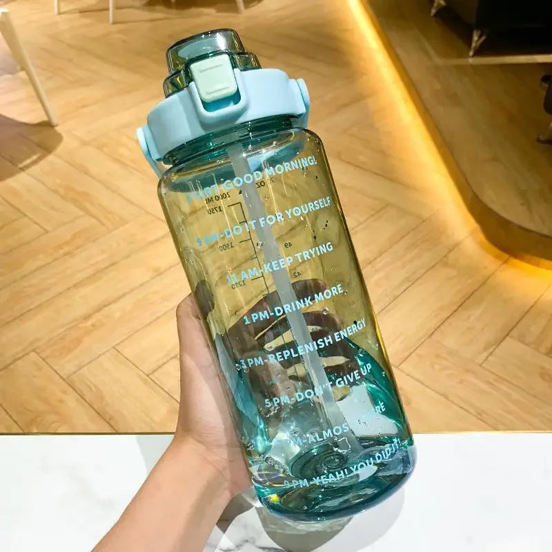 Une main tient une bouteille d'eau sportive transparente avec des marqueurs de temps, un cap bleu clair et du liquide vert.