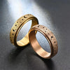 A pair of gold-toned stainless steel spinning rings featuring a moon and star design, resting on a dark surface.