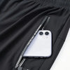 A white smartphone is placed inside a zippered pocket of black breathable men's casual jogger pants.