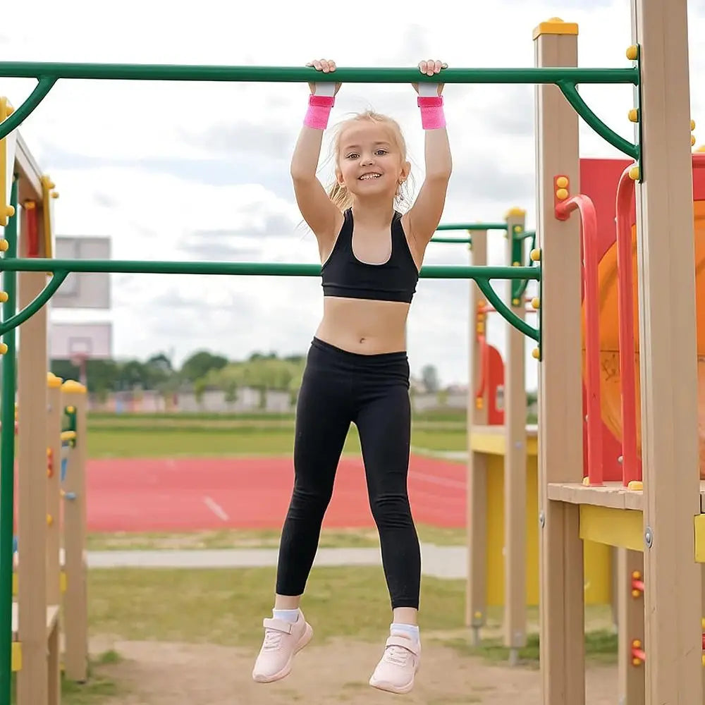 A young girl wearing a black sports outfit is holding onto a green bar during gymnastics practice.
