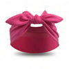 Un bandeau élastique rose noué en nœud, utilisé comme pare-soleil ou chapeau.