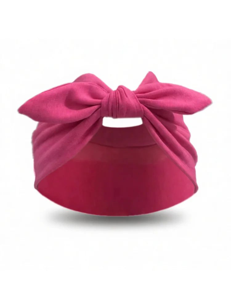 Un bandeau élastique rose noué en nœud, utilisé comme pare-soleil ou chapeau.